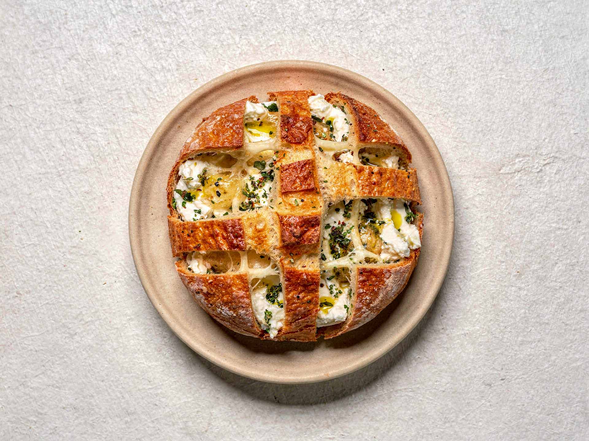 Knuspriges Ofenbrot mit geschmolzenem Käse und feinen Kräutern, eingeschnitten und goldbraun gebacken – ideal zum Teilen und Dippen.
