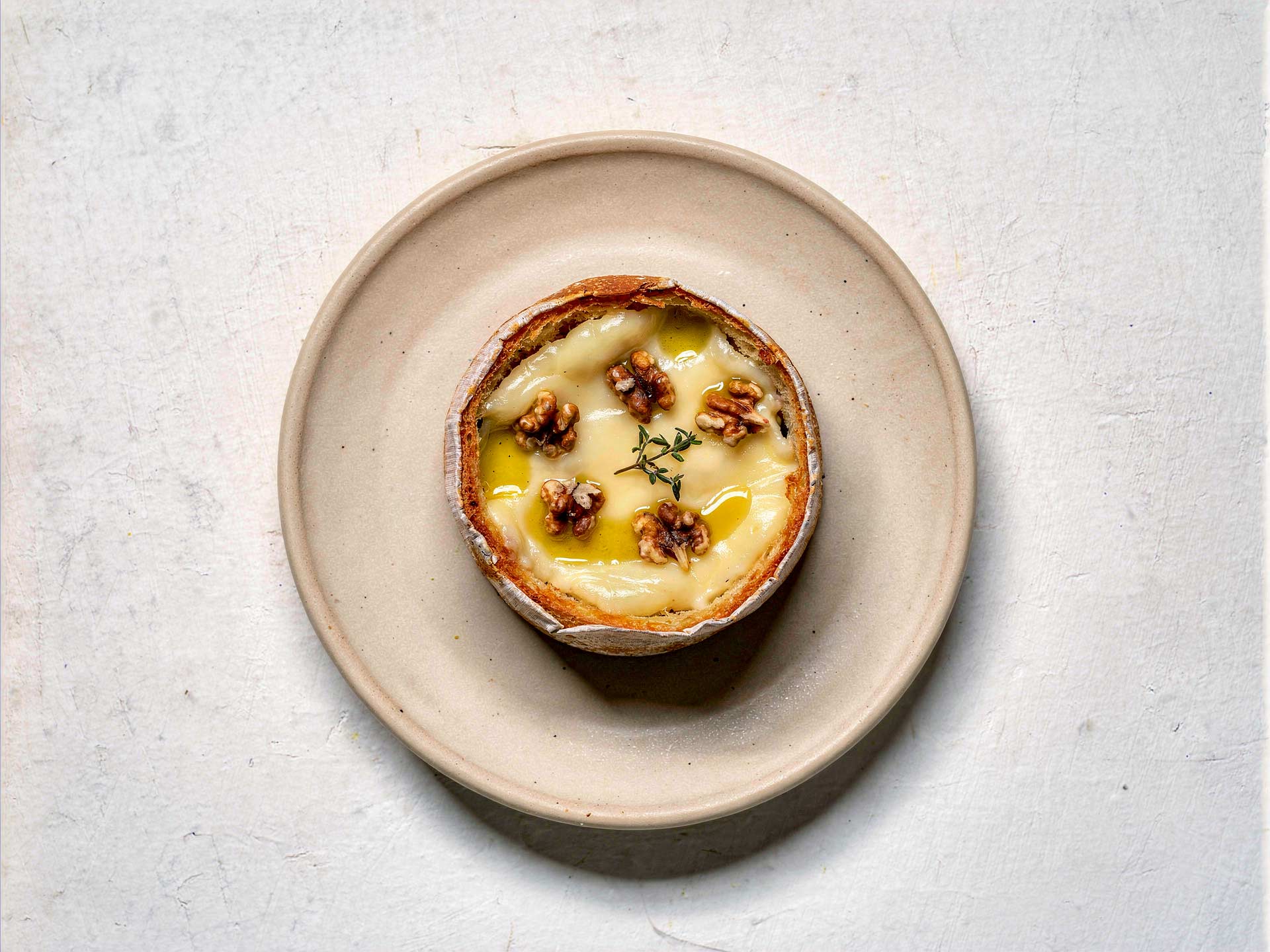 Warmer Ofencamembert mit geschmolzenem Käse, verfeinert mit Nüssen und einem Hauch Öl – ideal zum Dippen mit frischem Brot.