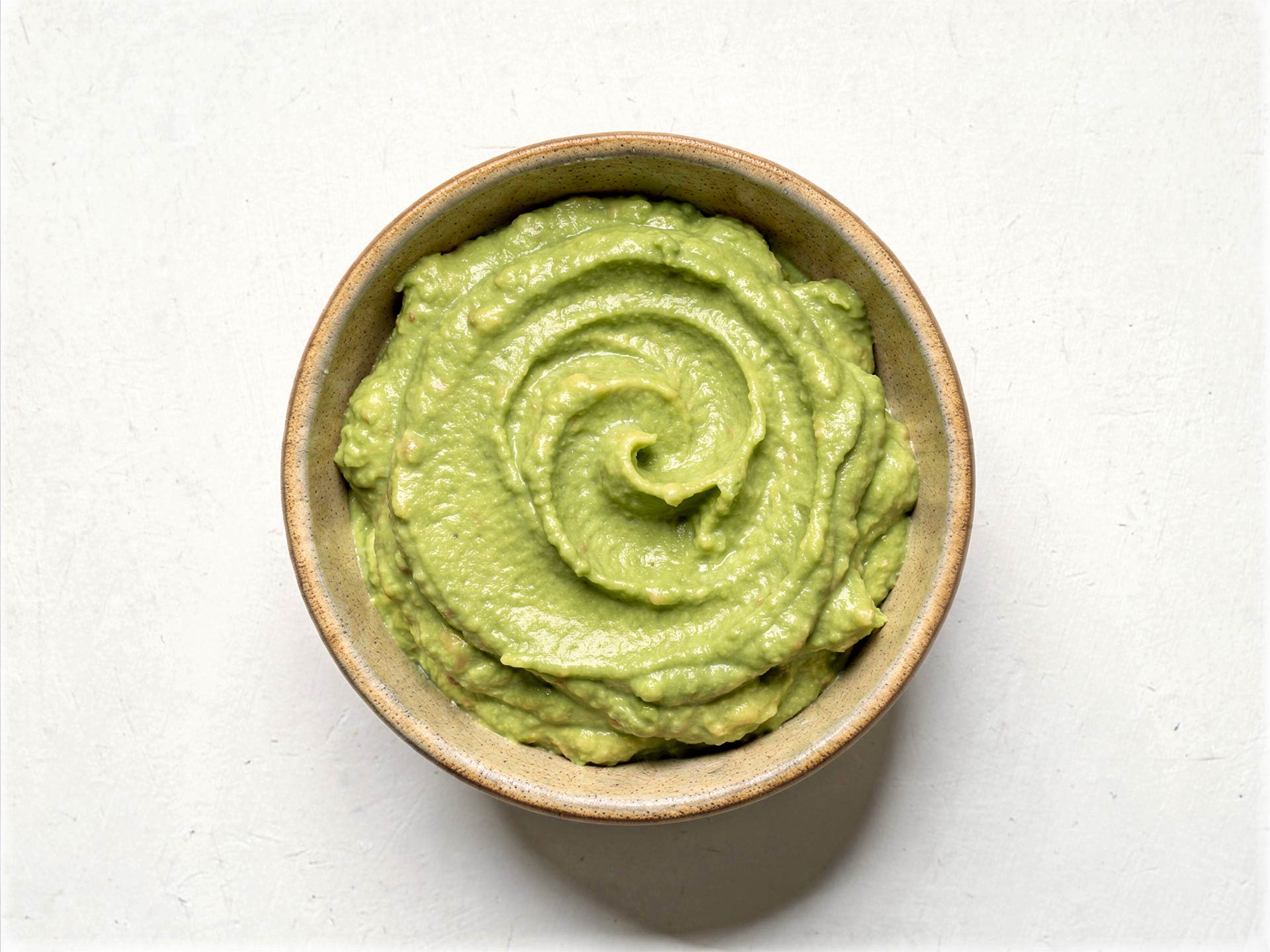 Cremiger Avocado-Limette-Dip in einer Schale, glatt gerührt mit feiner Spiralstruktur – ideal als Aufstrich oder Begleiter zu frischem Brot.