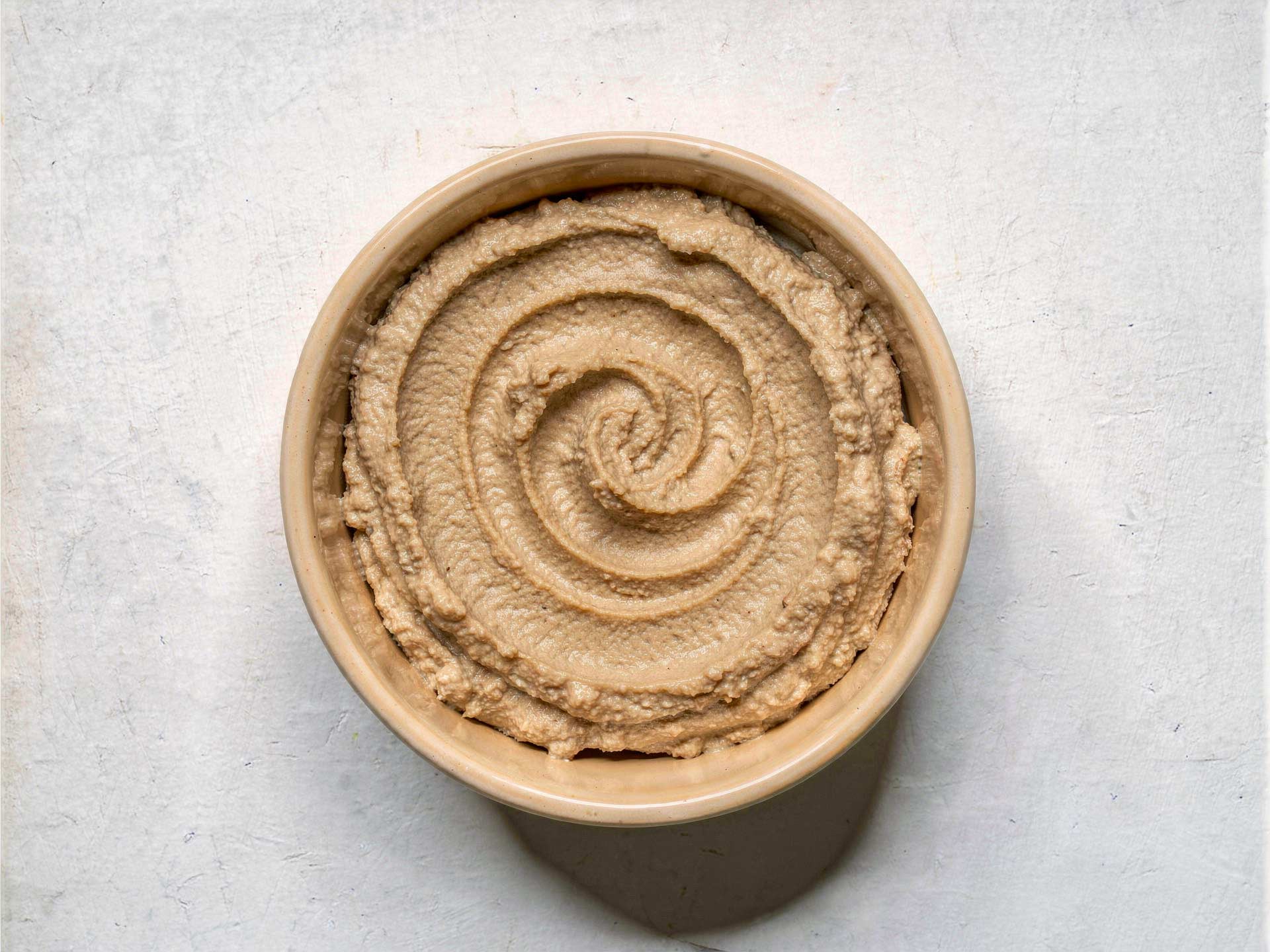 Cremiger Hummus-Dip in einer Schale, glatt gerührt mit feiner Spiralstruktur – ideal als Aufstrich oder Begleiter zu frischem Brot.